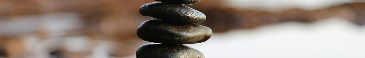 A stack of smooth stones artfully balanced by a waterside, evoking tranquility and zen.